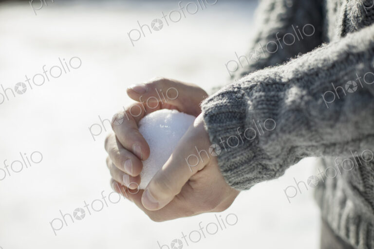 A man holding a large snowball in his bare hands.