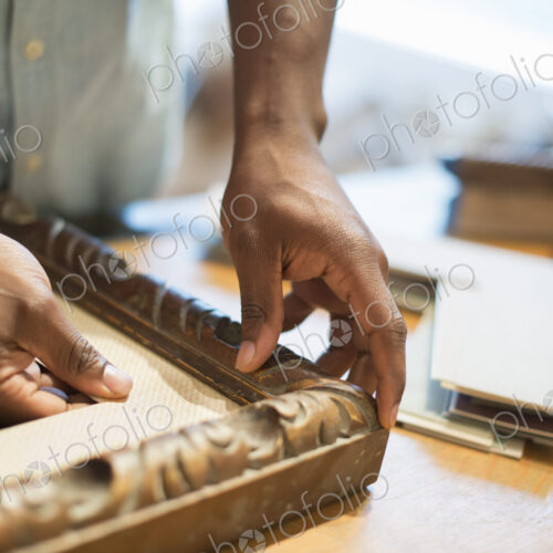 A man holding samples of picture mounts and frames, selecting colour and style.