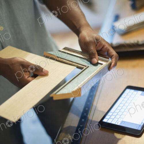 A man holding samples of picture mounts and frames, selecting colour and style. Using…
