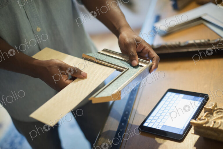 A man holding samples of picture mounts and frames, selecting colour and style. Using…