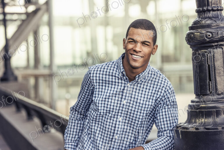 A man in a blue shirt leaning on a railing in a city park