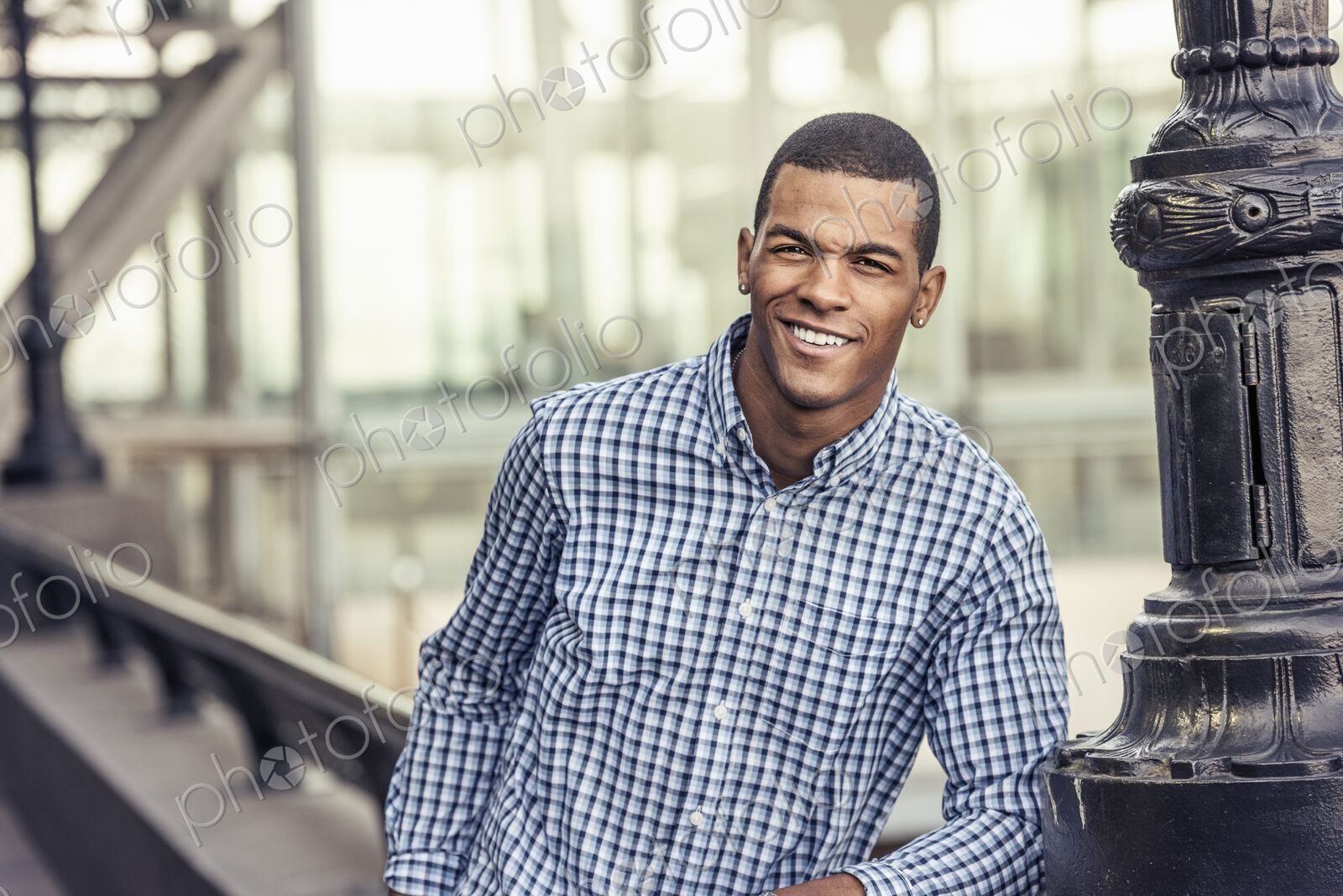 A man in a blue shirt leaning on a railing in a city park