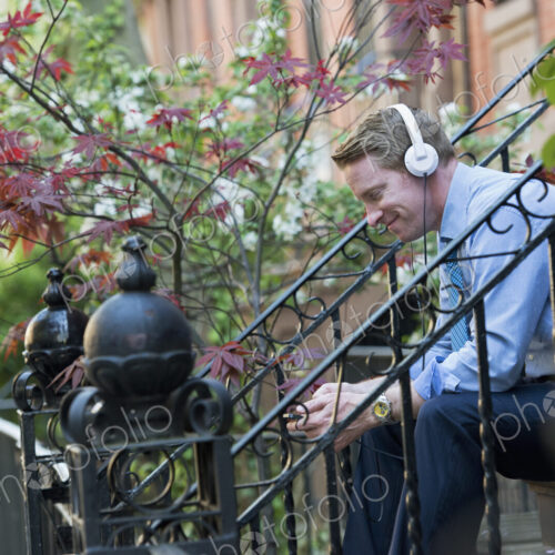 A man in a blue shirt wearing headphones and listening to a music player. Sitting on a… A man in a blue shirt wearing headphones and listening to a music player. Sitting on a…