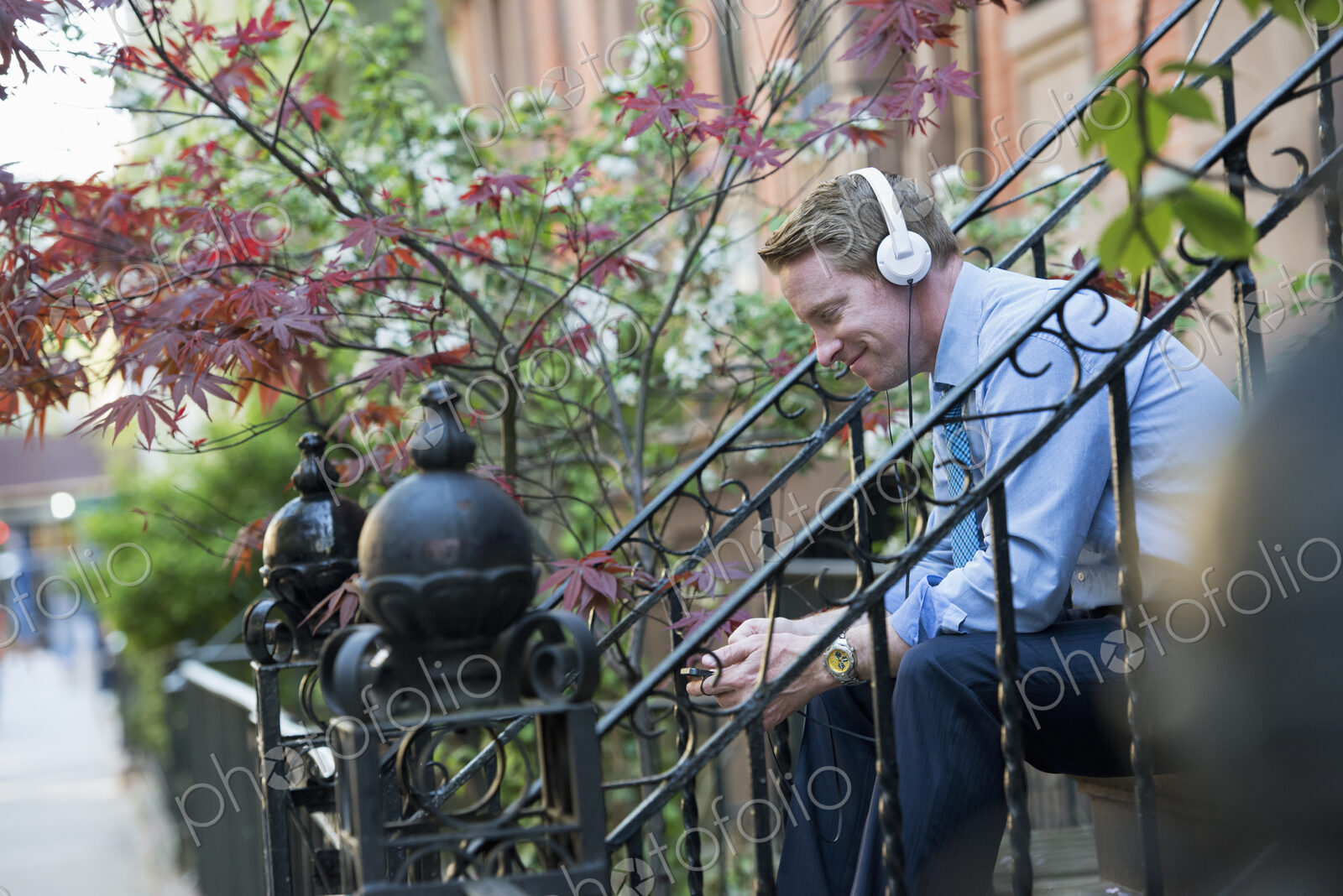 A man in a blue shirt wearing headphones and listening to a music player. Sitting on a…