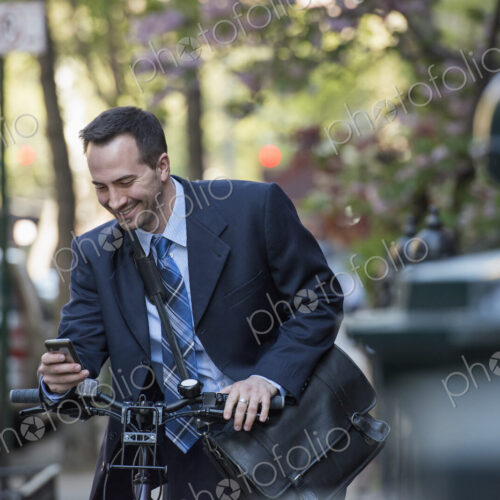 A man in a business suit, outdoors in a park. Sitting on a bicycle, with a cycle… A man in a business suit, outdoors in a park. Sitting on a bicycle, with a cycle…