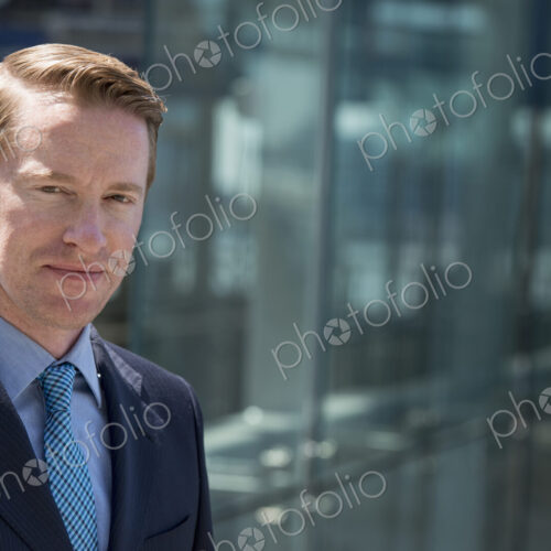 A man in a business suit outside a building with a glass exterior. A man in a business suit outside a building with a glass exterior.