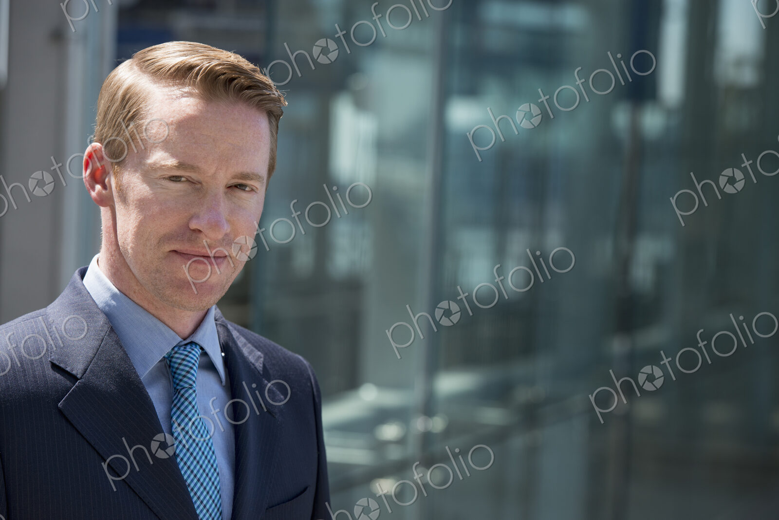 A man in a business suit outside a building with a glass exterior.