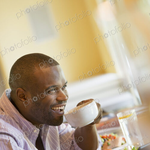 A man in a cafe holding a cup of coffee. A man in a cafe holding a cup of coffee.