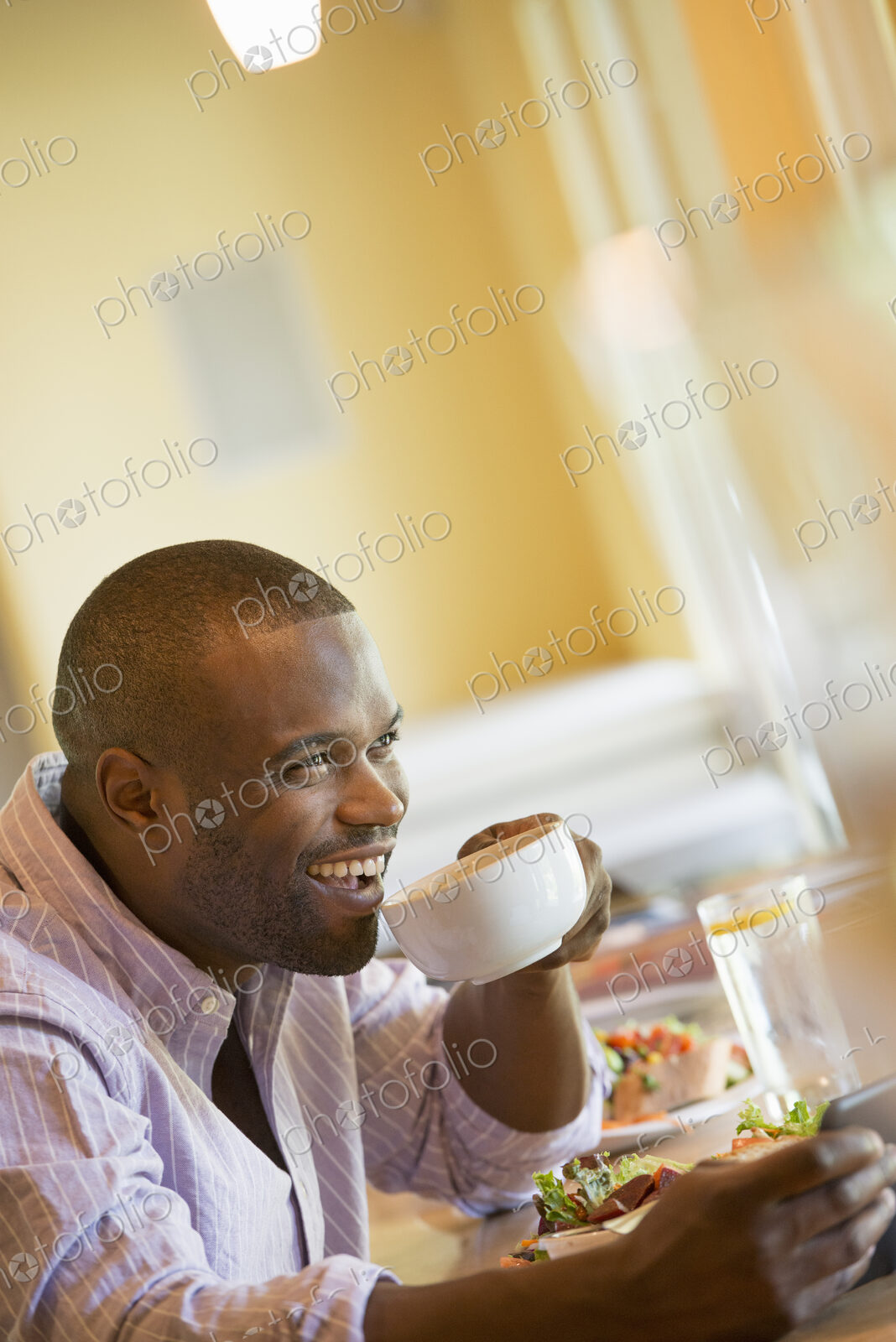 A man in a cafe holding a cup of coffee.