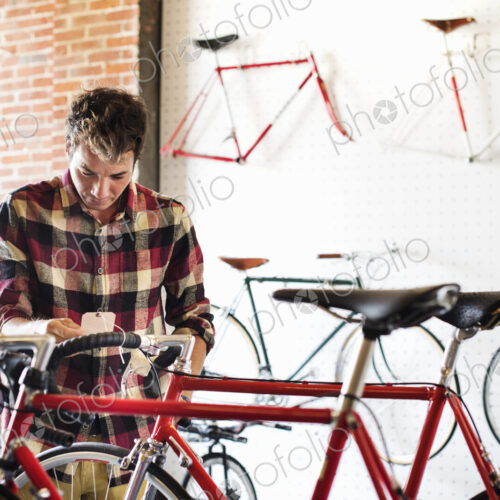 A man in a cycle shop, reading the price label on a bike. A man in a cycle shop, reading the price label on a bike.