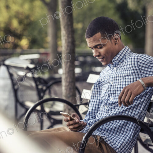 A man in a park looking at a smart phone A man in a park looking at a smart phone