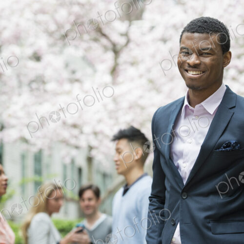 A man in a suit, people in the background using cell phones. A man in a suit, people in the background using cell phones.