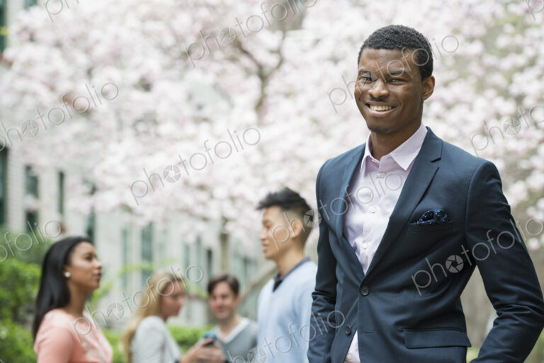 A man in a suit, people in the background using cell phones.