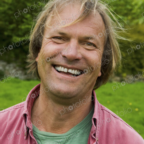 A man in casual clothes with blonde hair, smiling broadly. A man in casual clothes with blonde hair, smiling broadly.