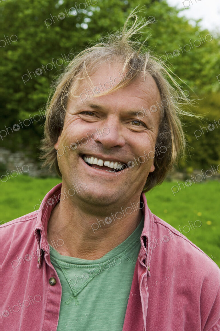 A man in casual clothes with blonde hair, smiling broadly.