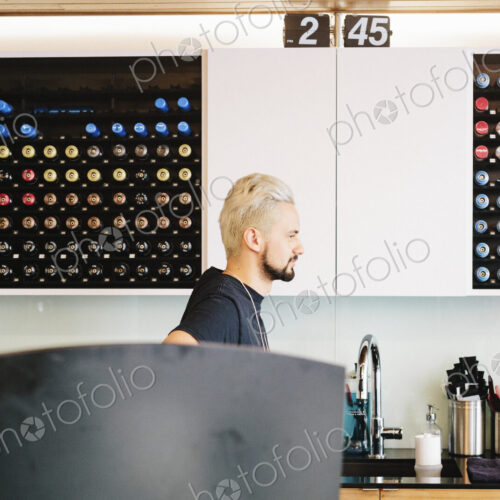A man in profile standing by a sink in a hair salon. A man in profile standing by a sink in a hair salon.