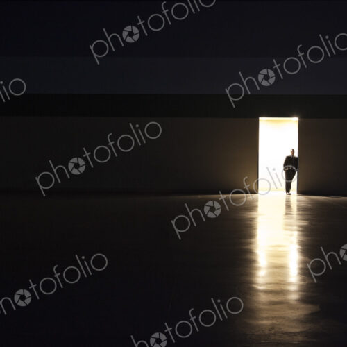 A man in silhouette standing in the doorway of a large convention center arena.
