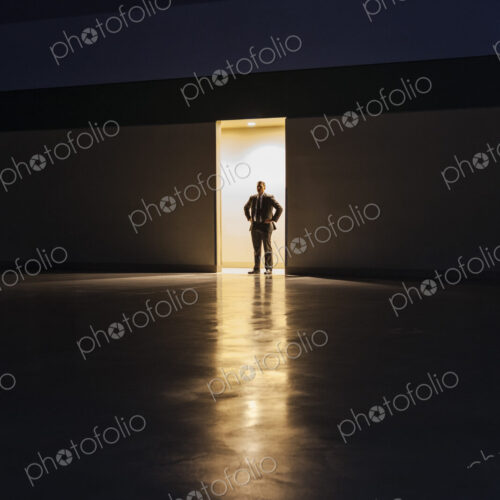 A man in silhouette standing in the doorway of a large convention center arena. A man in silhouette standing in the doorway of a large convention center arena.