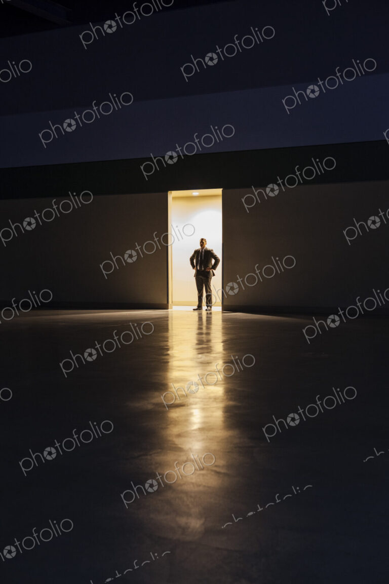 A man in silhouette standing in the doorway of a large convention center arena.