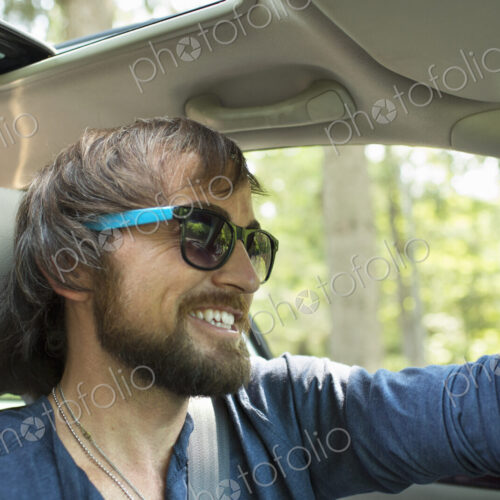 A man in sunglasses in the driving seat of a car.