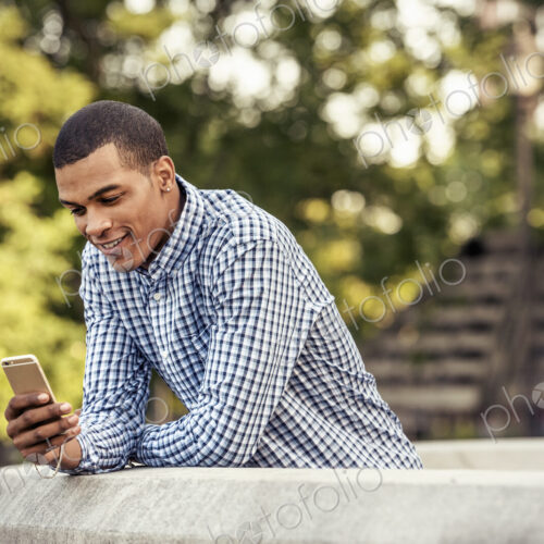 A man leaning on a parapet looking at a smart phone A man leaning on a parapet looking at a smart phone