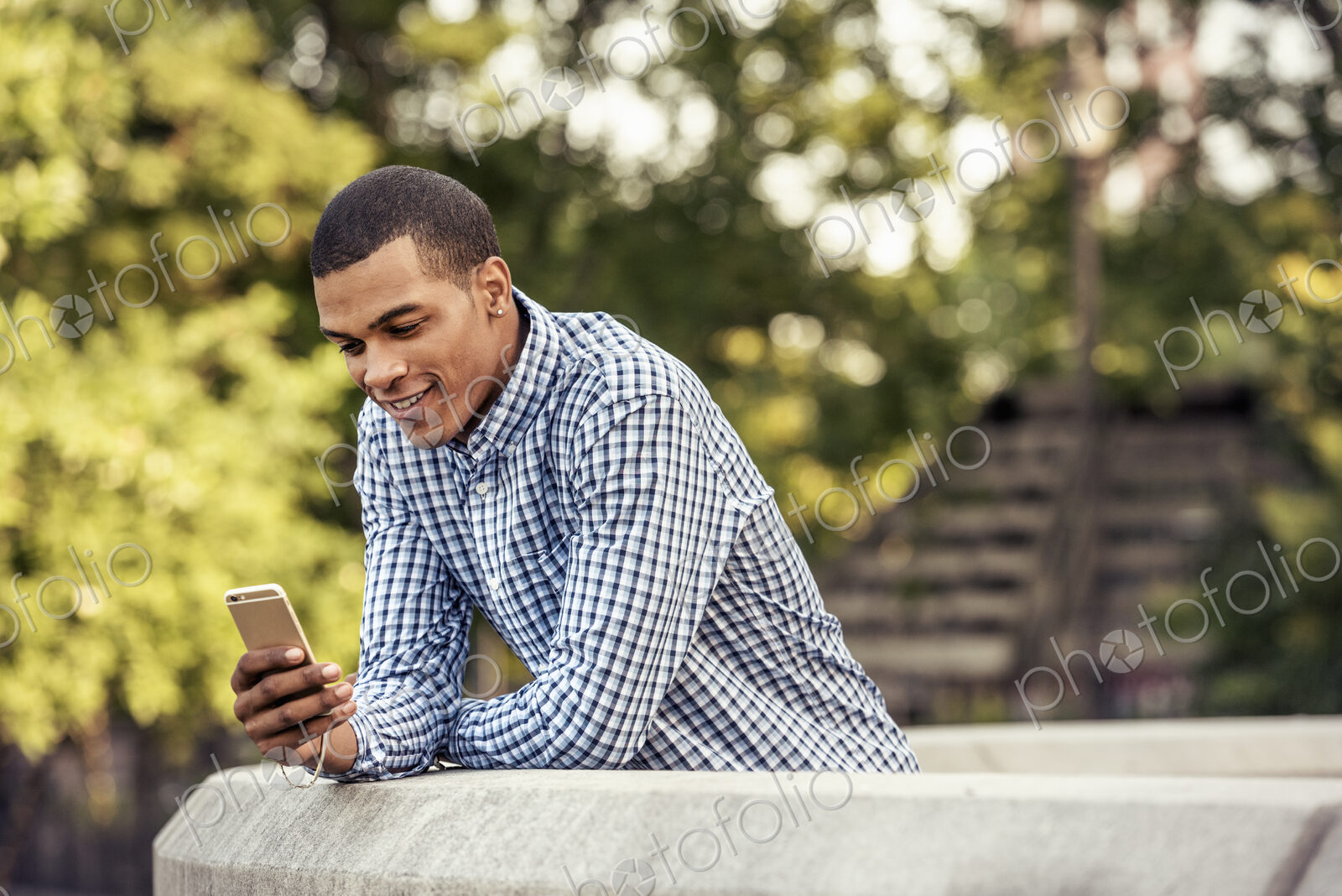 A man leaning on a parapet looking at a smart phone