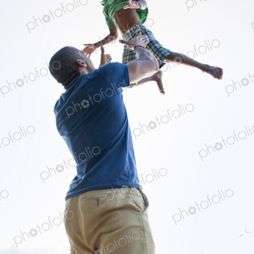 A man lifting a small boy up above his head in play. A man lifting a small boy up above his head in play.
