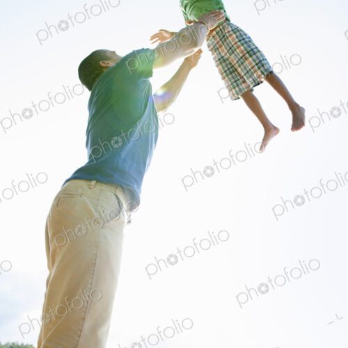 A man lifting a small boy up above his head in play. A man lifting a small boy up above his head in play.