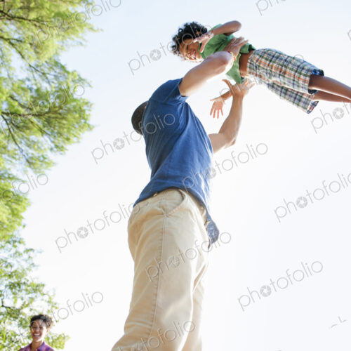 A man lifting a small boy up above his head in play. A man lifting a small boy up above his head in play.