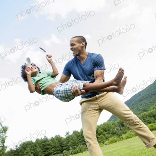 A man lifting his son up in his arms, playing outdoors. A man lifting his son up in his arms, playing outdoors.