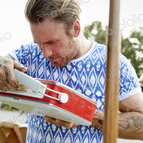 A man looking at a red vintage radio at a flea market. A man looking at a red vintage radio at a flea market.