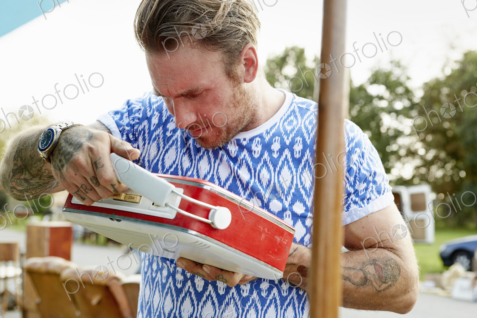 A man looking at a red vintage radio at a flea market.