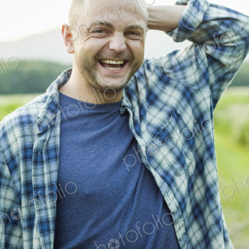 A man outdoors in a wild flower meadow wearing a checked shirt. A man outdoors in a wild flower meadow wearing a checked shirt.