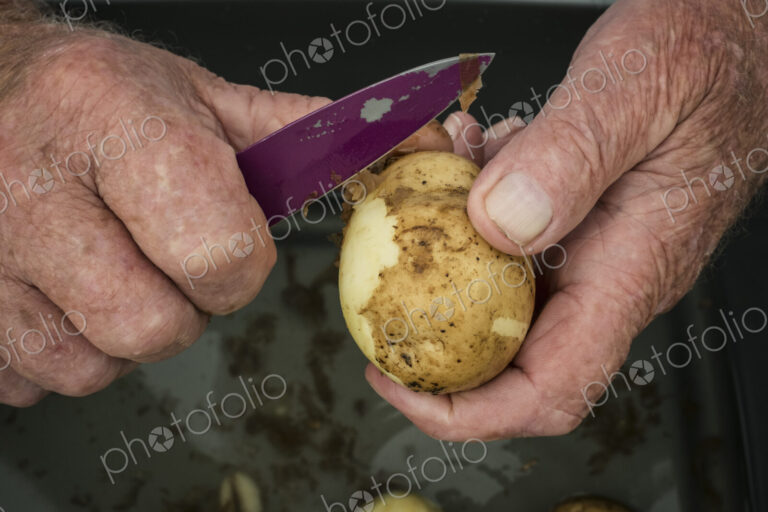 A man peeling a potato with a knife.