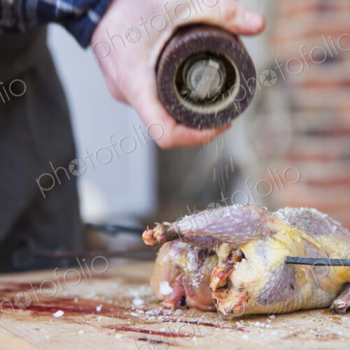A man preparing and seasoning game birds for roasting. A man preparing and seasoning game birds for roasting.
