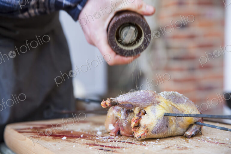 A man preparing and seasoning game birds for roasting.