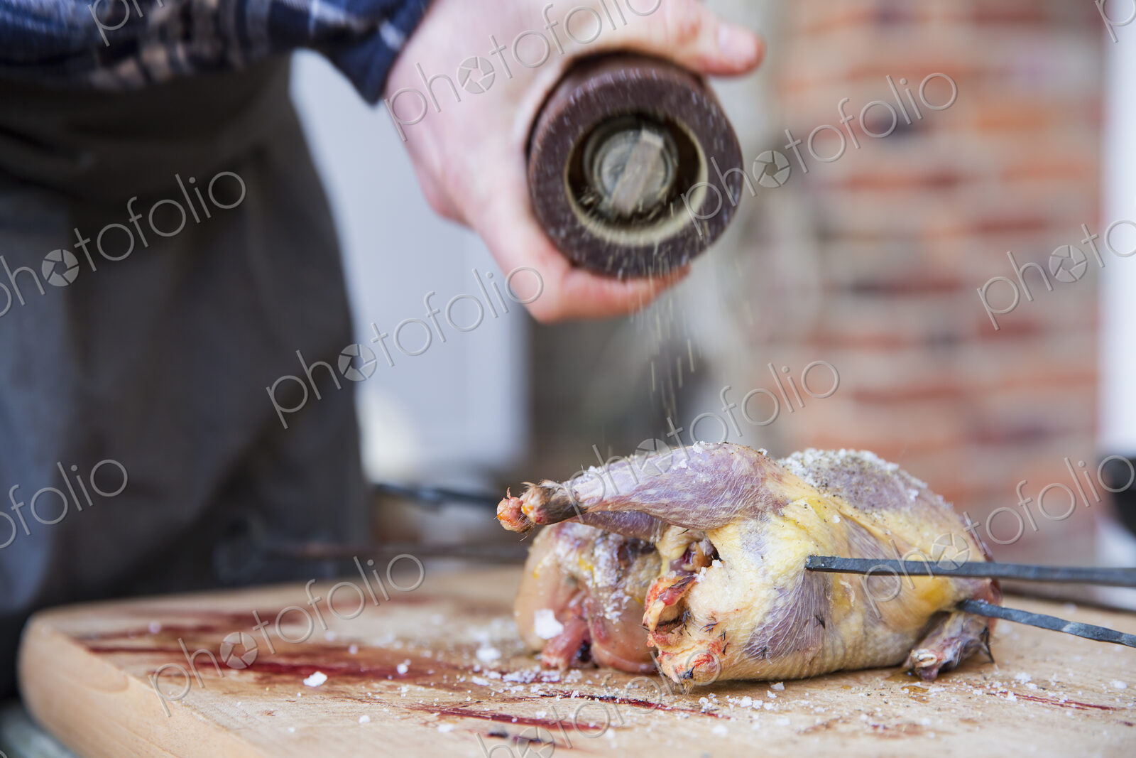 A man preparing and seasoning game birds for roasting.