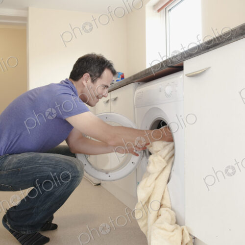 A man putting the laundry into the washing machine.