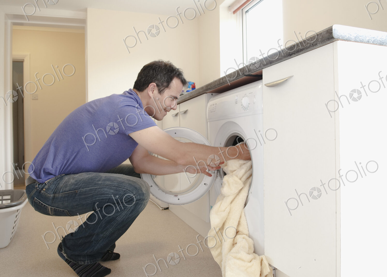 A man putting the laundry into the washing machine.
