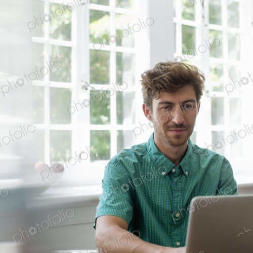 A man seated at a table using a laptop. Working from home. A man seated at a table using a laptop. Working from home.