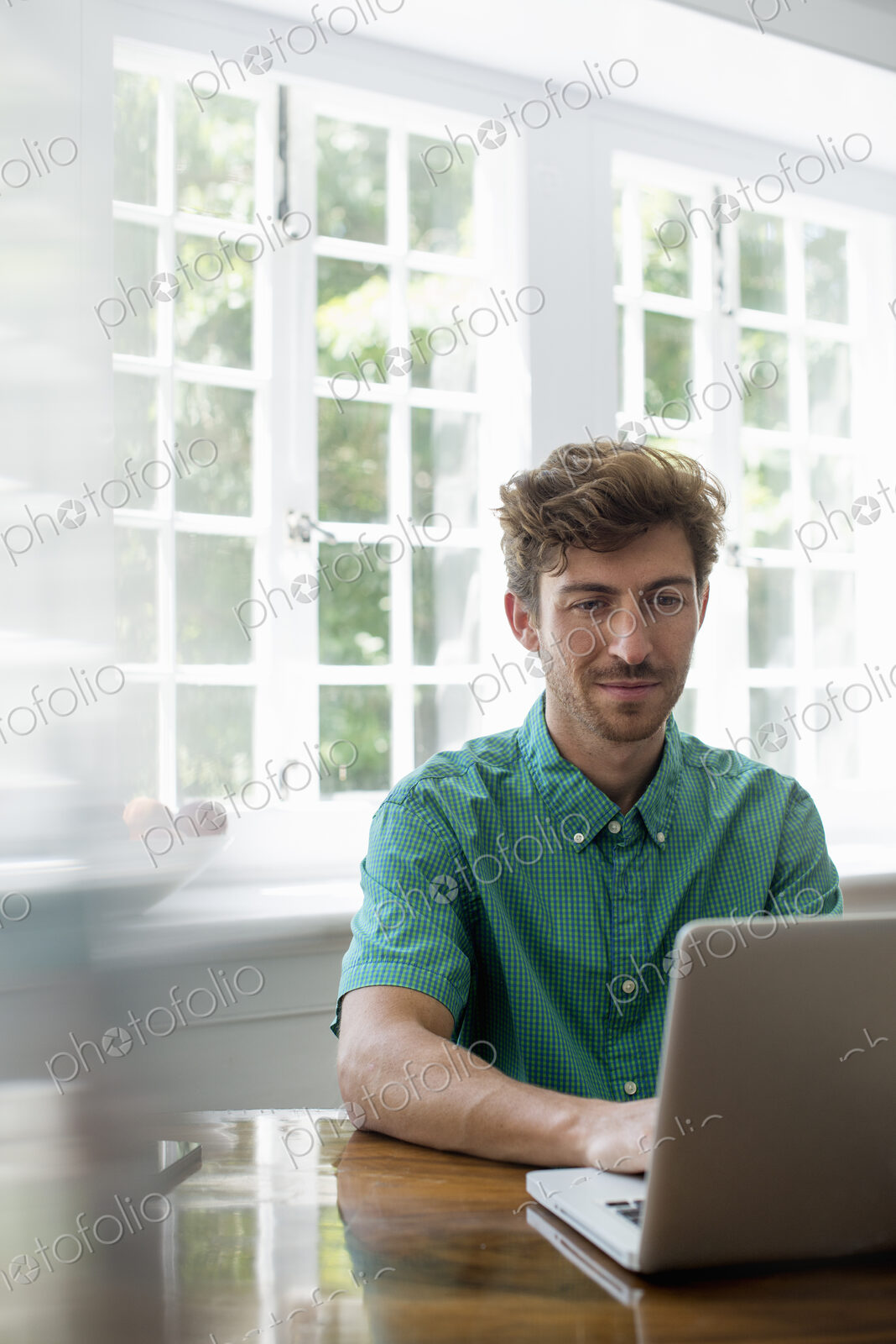 A man seated at a table using a laptop. Working from home.
