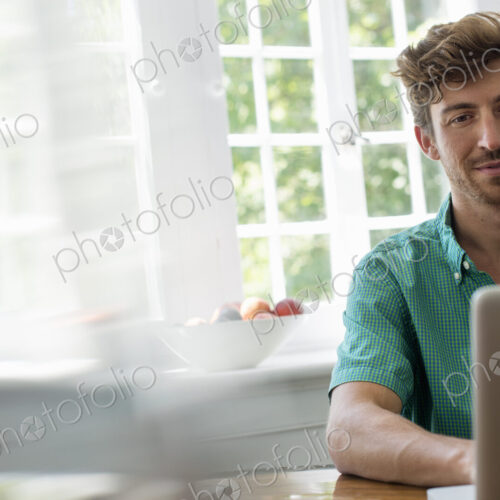 A man seated at a table using a laptop. Working from home. A man seated at a table using a laptop. Working from home.