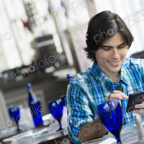 A man seated in a cafe using a smart phone. A man seated in a cafe using a smart phone.