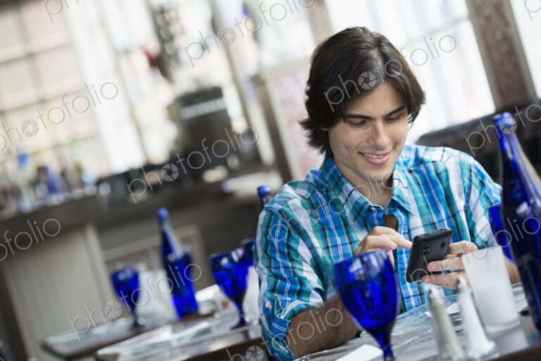 A man seated in a cafe using a smart phone.