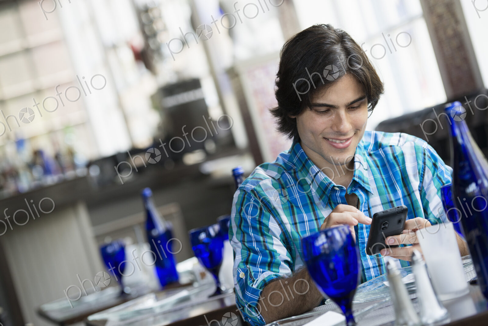 A man seated in a cafe using a smart phone.