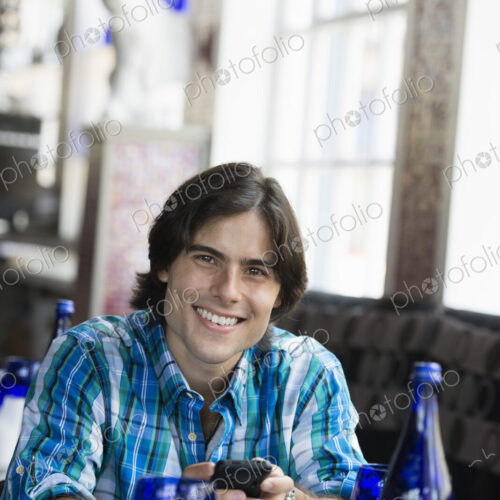 A man seated in a cafe using a smart phone. A man seated in a cafe using a smart phone.