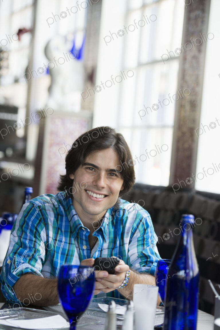 A man seated in a cafe using a smart phone.