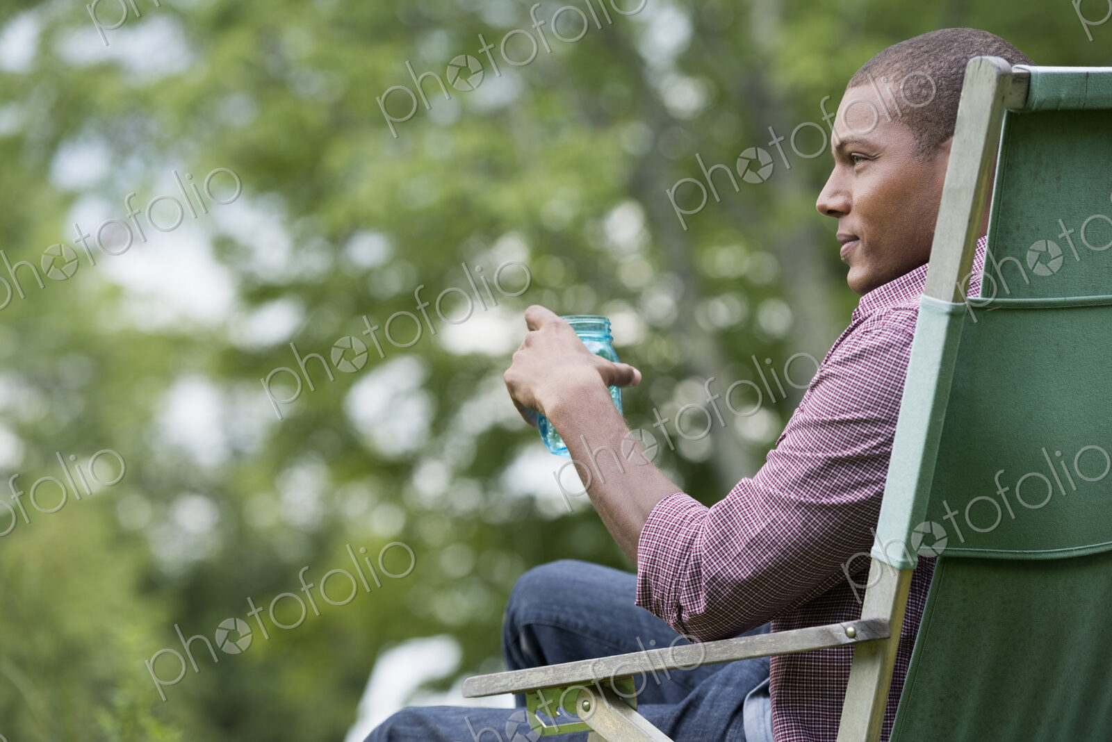 A man seated in a chair in a garden, relaxing.
