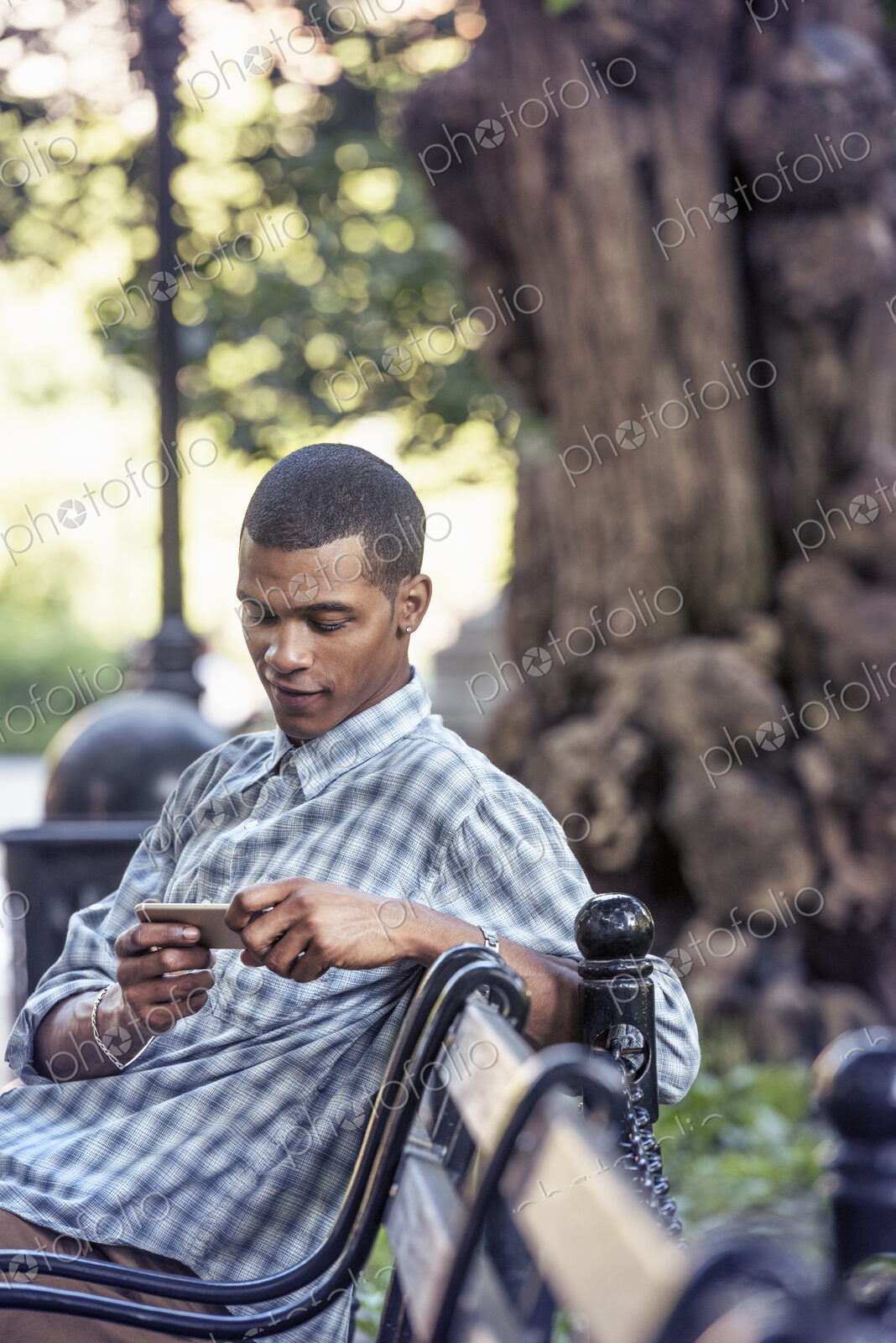 A man seated on a park bench using his smart phone