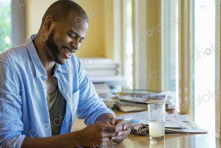 A man sitting alone in a cafe, using his smart phone.